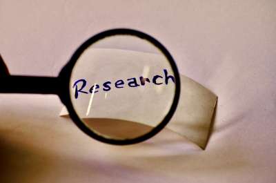 Black magnifying glass hovering over the word research